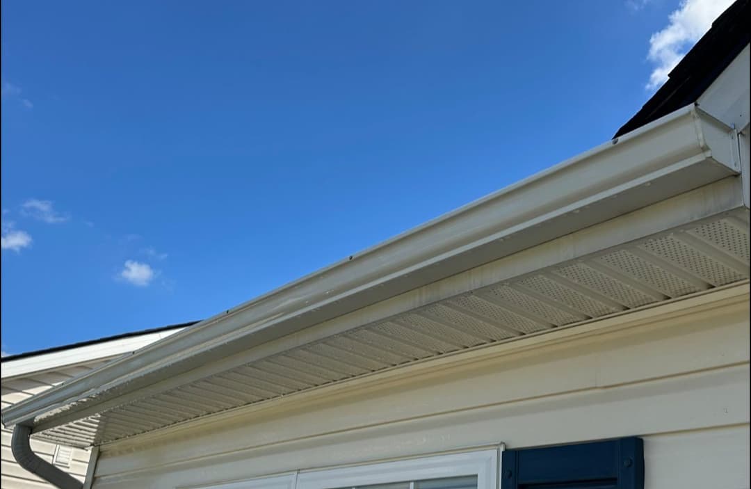 Clean white gutter along house eaves under a clear blue sky.