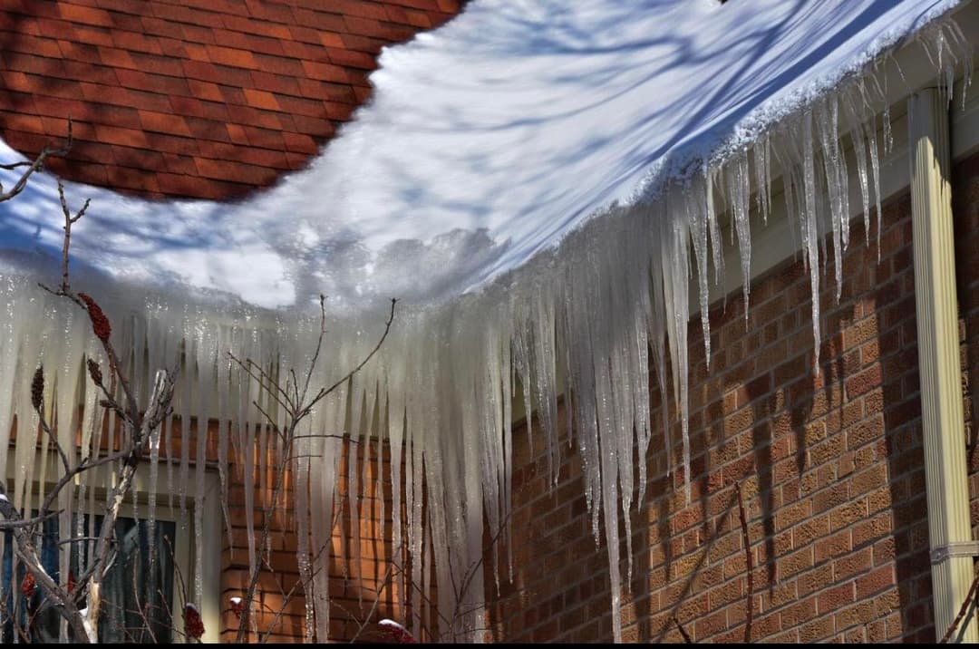 Icicles hanging from a roof with snow, showcasing winter weather and home exterior details.